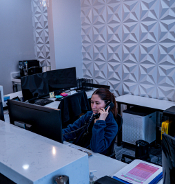 Reception area of Smile Avenue Cypress TX Family Dentist with staff member assisting a patient call. Modern and welcoming dental practice interior showcasing customer service focus in cosmetic dental care.