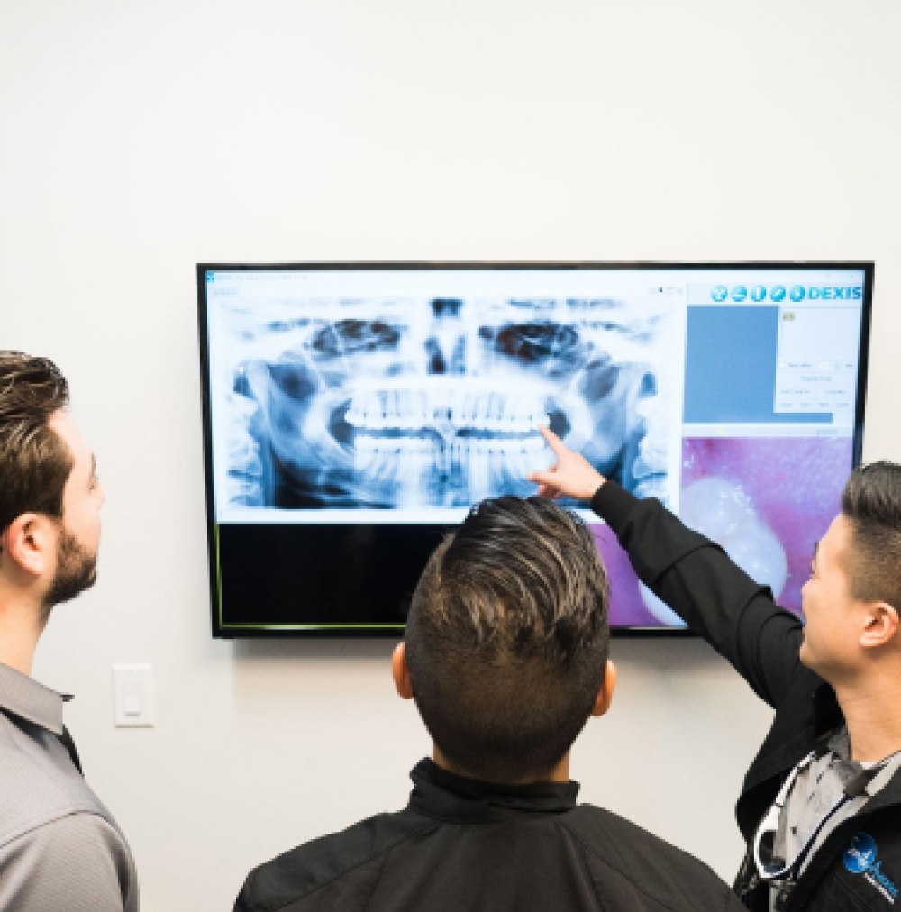 Dentist showing dental X-ray to patients in Cypress, TX family dental office, Smile Avenue.