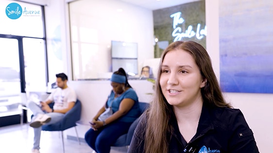 Waiting area at Smile Avenue Family Dentistry with a focus on patient experience. A patient smiles and talks while two others wait in the background, showcasing a comfortable and welcoming dental clinic environment in Katy.