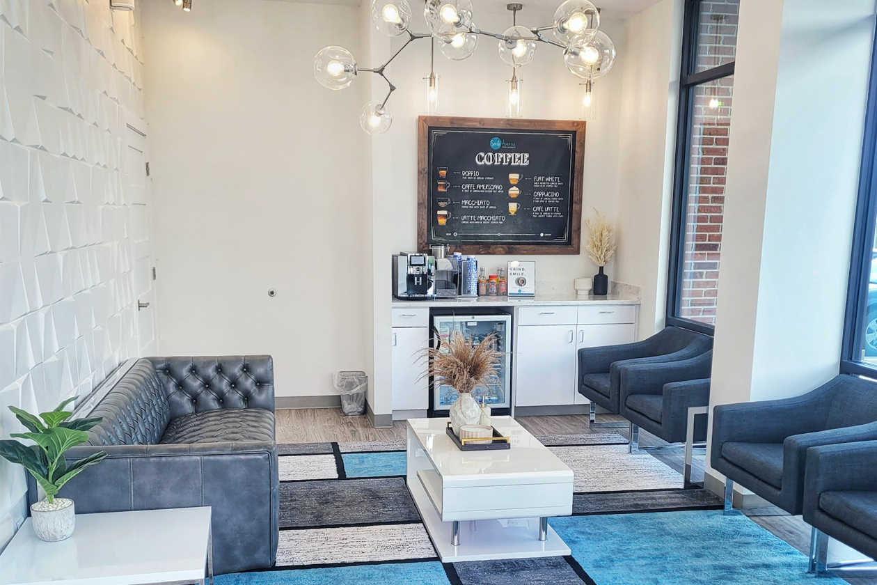 Modern and inviting interior of Smile Avenue Family Dentistry in Katy, TX, featuring a comfortable waiting area with plush seating, a stylish coffee station, and contemporary decor.