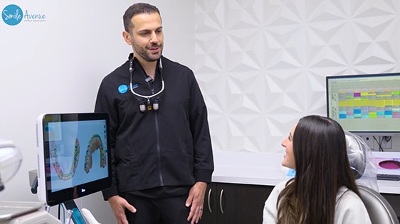 Dentist explains dental procedure to a patient in a modern dental office, featuring a screen displaying a dental scan. Patient Education & Smile Tips at Katy Dental Video Library.