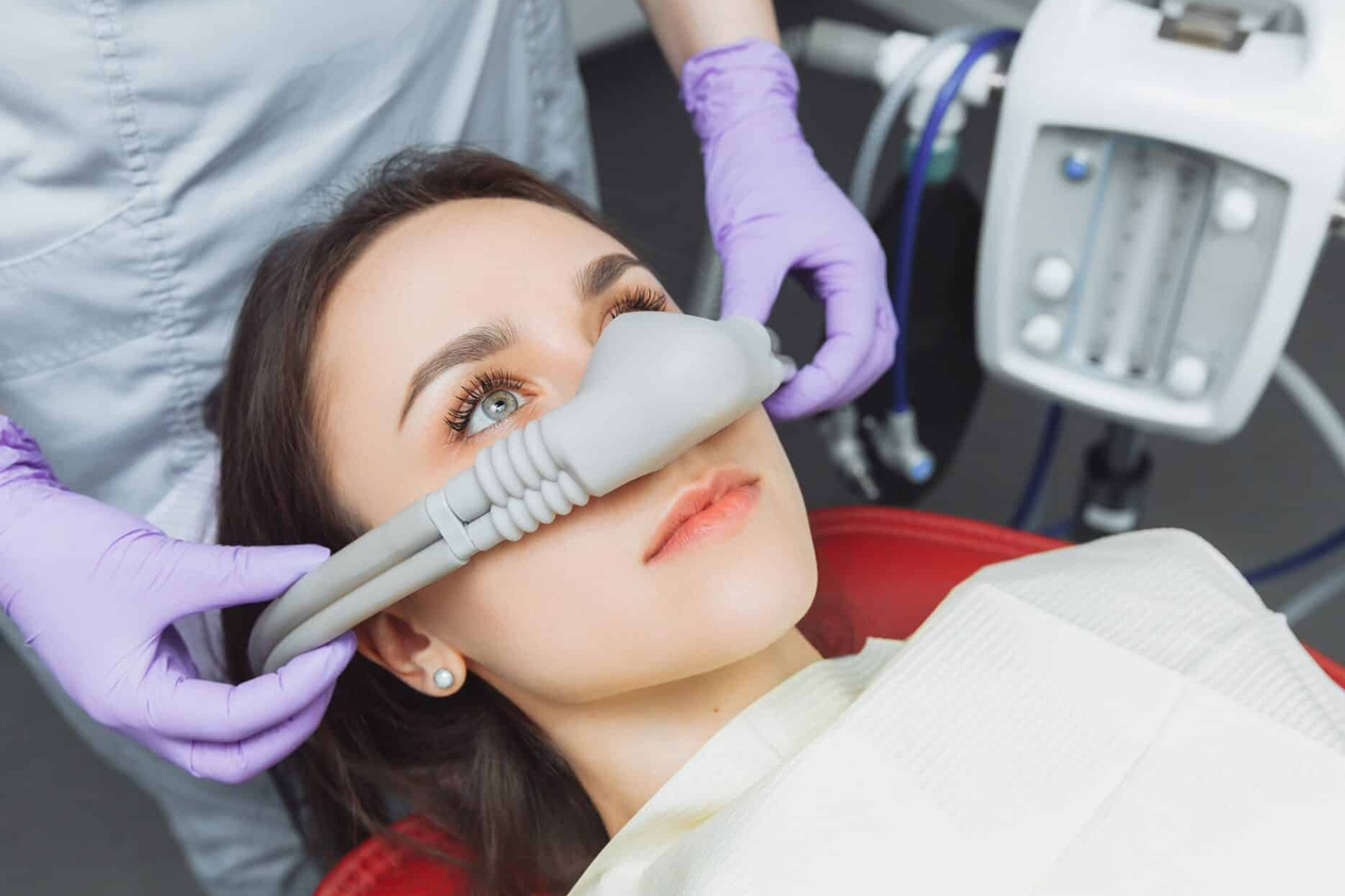 Patient receiving sedation dentistry with nitrous oxide mask, overseen by a dentist wearing purple gloves, at a Katy dental clinic focused on anxiety-free care.