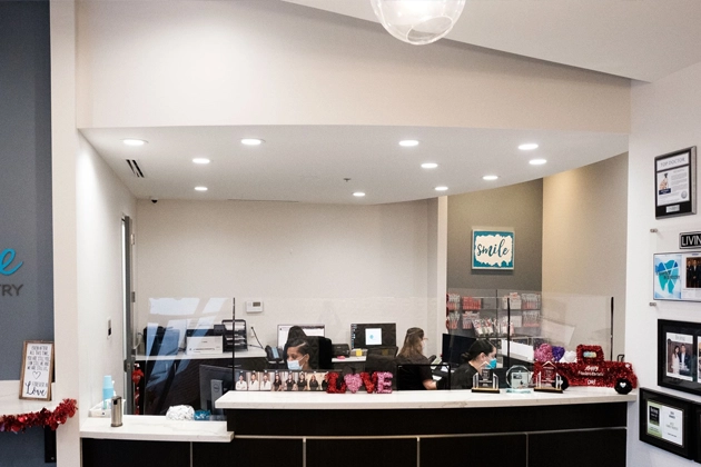Reception area of Smile Avenue Dental Office in Cypress, TX, featuring front desk with employees and dental decor, inviting patients to book family appointments.