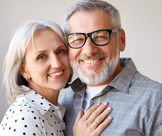 Smiling older couple embracing, symbolizing happiness and confidence after receiving dental implants in Katy, TX. Permanent tooth replacement solutions for improved dental health and quality of life.