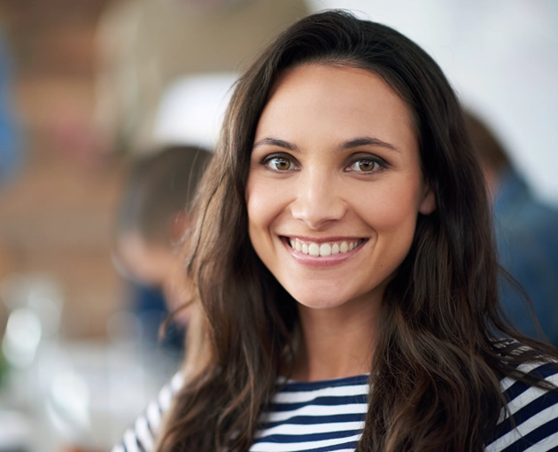 Smiling woman with long hair wearing a striped shirt, representing confidence in dental health services in Cypress, TX.