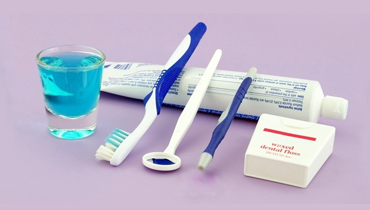 Dental hygiene tools including a toothbrush, toothpaste, dental floss, and mouthwash promoting advanced dental technology for a beautiful smile in Katy.