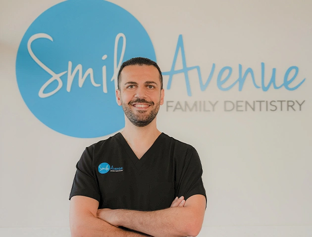 Dr. Laith standing confidently in front of Smile Avenue Family Dentistry sign, exemplifying holistic family dental care in Katy.