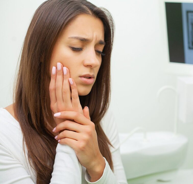 Woman experiencing tooth pain, holding her cheek in discomfort, symbolizing the need for emergency dental care in Cypress, TX.