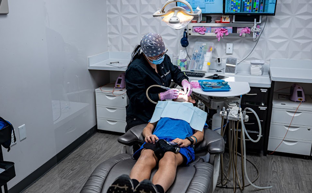Dentist providing care to a patient in a modern, well-equipped dental office in Cypress, TX. Dental chair positioned in a clean, professional environment, highlighting affordable new patient dental care at Smile Avenue.