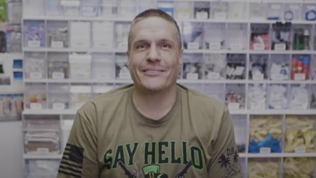 Man sitting in a dental clinic, smiling with a background of organized dental supplies.