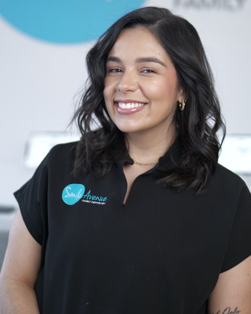 Smiling dental professional at Smile Avenue Family Dentistry in Cypress and Katy, TX, showcasing friendly service in a modern dental office setting.