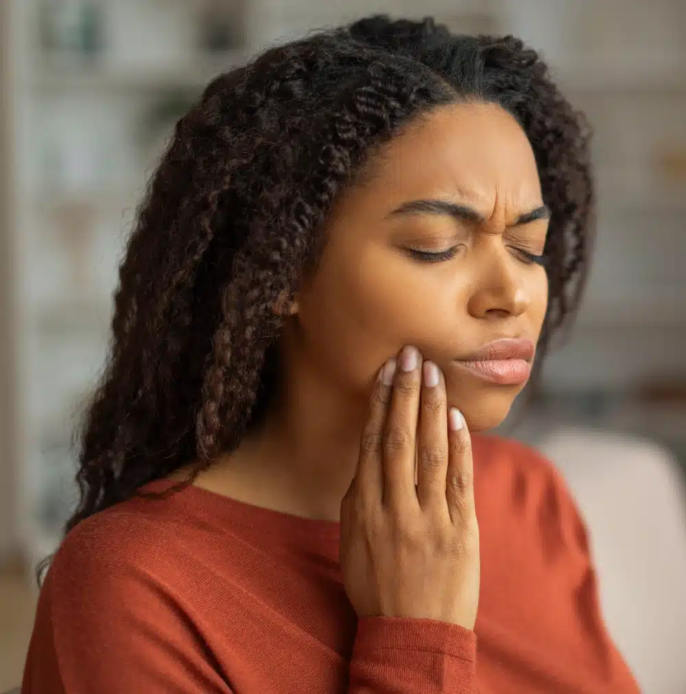 Emergency Dentist Katy, TX OLD1 1 Woman with curly hair touching her cheek appearing to have tooth discomfort