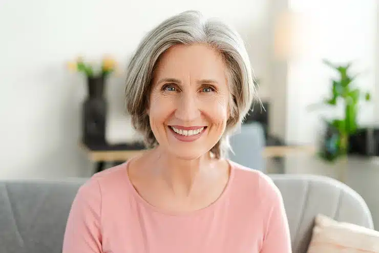 Dental Implant Cypress TX 1 Older Woman In A Pink Top Smiling In A Bright Indoor Setting