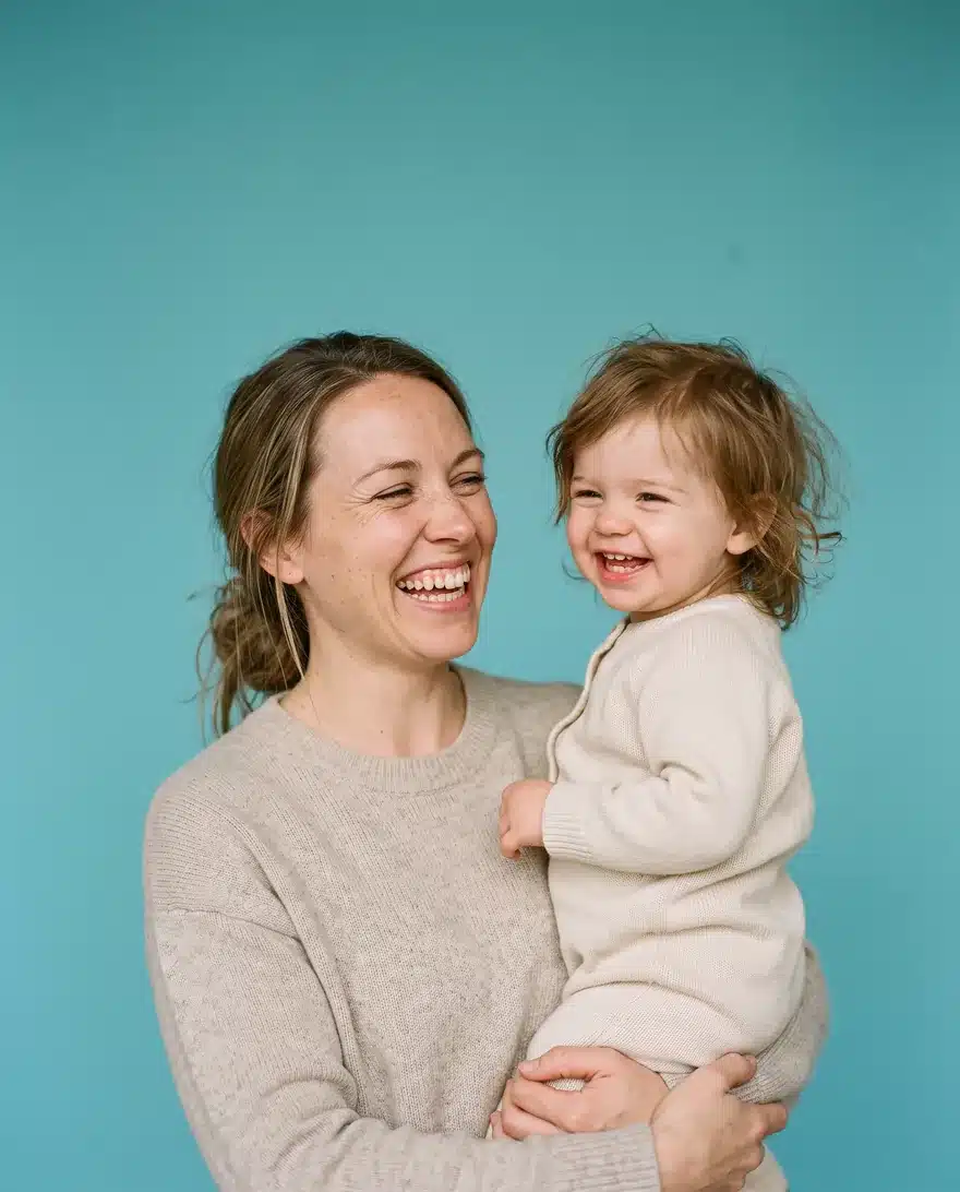 A mother laughing with her toddler on her hip
